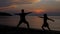Mother does yoga asana and jumping daughter on sunset background