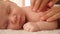 Mother doing massage on her healthy sleeping infant baby. Small caucasian newborn resting and laying on his belly while his mother