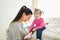 Mother dressing her daughter in the morning in bedroom