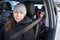 Mother driving a car with her little son sitting in child safety seat on back, safety belt