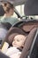Mother driving, with her baby boy in a child seat