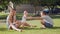 Mother and elder brother spin and walk with girl baby toddler making first steps on park grass.