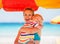 Mother embracing baby on beach under umbrella