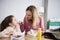 Mother examining daughter`s teeth while preparing lunch box with sweets