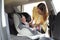Mother fastening baby to child safety seat