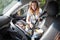 Mother fastening child safety seat with her little baby on front passenger seat, infant sits with his back to the engine