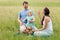 Mother and father and daughter blowing bubbles outdoors in summe