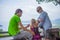 Mother, father and daughter sit on side and look around from mountain view point on tropical beach island