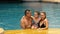 The mother and father with little daughter have fun in the pool. Mom and dad plays with the child. The family enjoy
