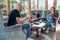 Mother, father and son family sitting together at Sunroom in cozy armchairs and reading books, using laptop or browsing a