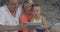 Mother,father and son watching video on pad while sitting on beach