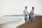 Mother and father with their son walking together on a quiet beach