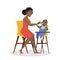 Mother feed her little baby sitting in highchair