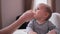 Mother feeding baby girl in highchair