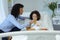 Mother feeding her son orange juice in bed in the ward