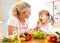 Mother feeding kid vegetables in kitchen