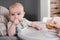 Mother feeding with vegetables or fruits pure baby on highchair