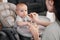 Mother feeding with vegetables or fruits pure baby on highchair