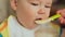 Mother feeds her capricious child. Gives him porridge and gives him juice. Face close-up.