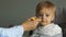 Mother feeds her little daughter sitting in a highchair. Girl got dirty food, healthy eating