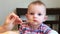 Mother feeds little daughter with fruit puree from a spoon