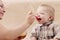 Mother feeds  small child with fruit puree