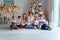 Mother and five children playing sparkler near Christmas tree at home