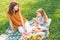 Mother and girl having some fruits for picnic in the park at daytime