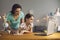 Mother and girl watching lesson conference teacher remotely sitting at table at home.