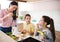 Mother with girls indoors at home, preparing fruit smoothie drink.