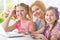 Mother and girls sitting at table and using laptop