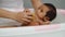 Mother give a bath newborn baby in bathtub