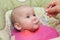 Mother gives baby food from a baby spoon. baby eating food first time. weaning baby