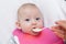 Mother gives baby food from a baby spoon. baby eating food first time. weaning baby