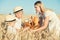 Mother gives children a basket with fresh bread and milk. A picnic on a wheat field.