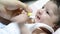 Mother gives small sliced quince to little baby mouth