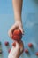 Mother giving her son a big red strawberry. Little boy taking a strawberry from mom`s hand. Little strawberries on bright blue