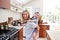 Mother Giving Smiling Daughter Piggyback Ride In Kitchen At Home