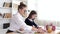 Mother in glasses helping brunette daughter to do homework at home