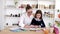 Mother in glasses helping brunette daughter to do homework at home