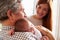 Mother And Grandfather With Sleeping Newborn Baby Daughter