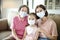 Mother and grandmother help daughter wearing face mask to prevent  air pollution and COVID-19 coronavirus