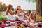 Mother, grandmother and kids weaving braids to each other. Family having fun during picnic in park. Women`s day