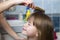 Mother hand with brush combing long fair hair of cute child girl after bath on blurred interior background