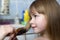 Mother hand with brush combing long fair hair of cute child girl after bath on blurred interior background