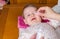 Mother hands cleaning eyes of baby with cotton