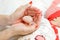 Mother hands with red nails holding newborn arm.