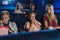 Mother with happy small children in the cinema, watching film.