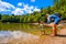 Mother help baby enter feet in lake water during family trip in nature of Foresta Umbra - Gargano Apulia - Italy