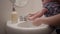 Mother helping baby toddler girl wash her hands with soap in bathroom